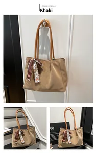 Detail of khaki soft leather tote bag featuring a decorative printed silk scarf on handle