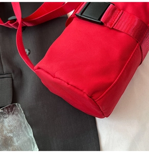 Close-up of a vibrant red travel shoulder bag featuring a durable nylon strap and black buckle