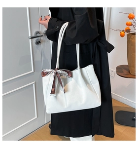 Detailed side view of white faux leather tote bag with decorative brown printed silk scarf