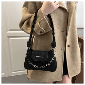 Detail of black suede shoulder bag with woven handle and silver floral chain accents