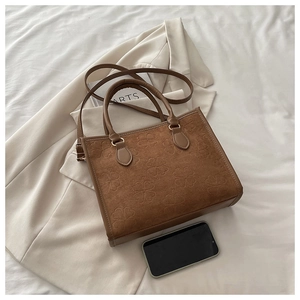 Dettaglio della borsa tote in pelle scamosciata marrone con motivo a trifoglio goffrato