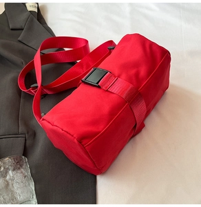 Detailed close-up of a vibrant red cylinder crossbody bag with durable nylon fabric texture