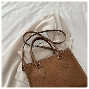Dettaglio borsa tote color caramello con motivi a trifoglio e finiture dorate