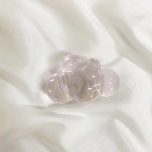 Close-up of a pink cloud-shaped hair claw clip on a soft white fabric background