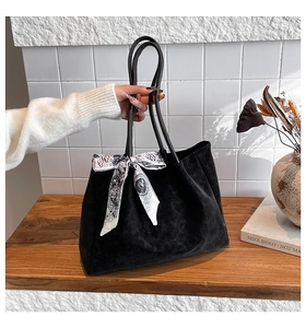 Detail of black velvet tote bag featuring a decorative printed silk scarf on the handle