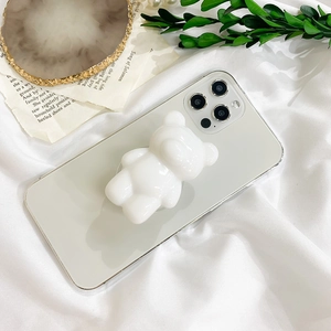 Close-up of a white 3D bear phone grip mounted on a silver smartphone back