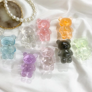 Flat lay of colorful semi-transparent resin gummy bear phone grips on white satin fabric