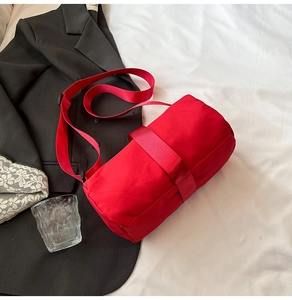 Close-up of red cylindrical crossbody bag made of waterproof nylon on white bedding