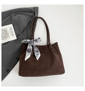 Macro detail of dark brown suede tote bag with stylish patterned scarf and sturdy handles