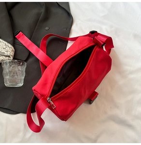 Detail of red nylon cylinder crossbody bag featuring wide strap and zipper closure