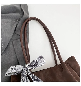 Detail view of dark brown suede tote bag with butterfly silk scarf and neat stitching