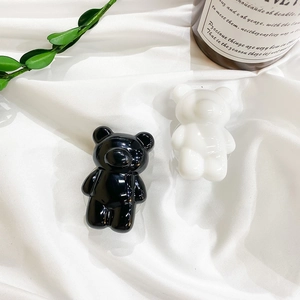 Detailed view of glossy black and white bear phone grips on elegant white silk fabric