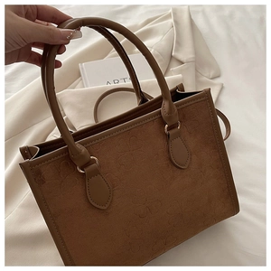 Dettaglio della borsa tote in finta pelle scamosciata marrone con trifogli goffrati e oro