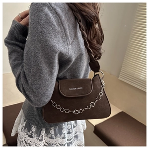 Detail of dark brown suede shoulder bag featuring a decorative silver floral metal chain