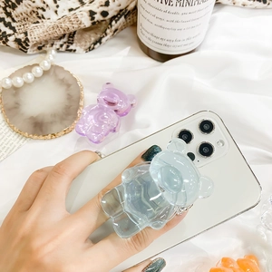 Detailed view of translucent bear-shaped resin phone grips on a white surface