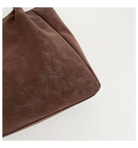 Macro detail of dark brown vintage tote bag showing textured leather finish and stitching