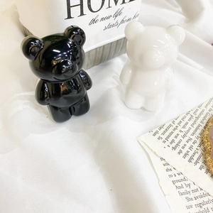 Macro shot of black and white ceramic bear figurines with glossy finish on white fabric