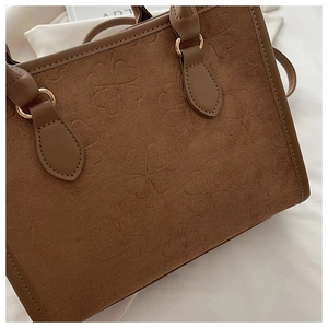 Dettaglio borsa tote in pelle scamosciata marrone con trama a quadrifoglio e anello dorato