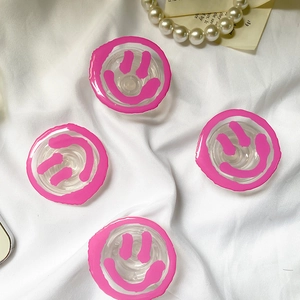 Detail view of 4 transparent cell phone grip stands with pink fluid smile graffiti
