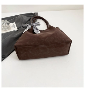 Detail view of large dark brown suede tote bag with decorative black and white silk scarf