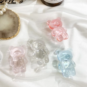Detail of four colorful gummy bear phone grips on white fabric with elegant accessories