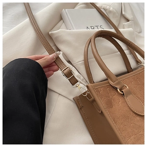 Dettaglio della borsa tote in pelle marrone con motivo a trifoglio e tracolla regolabile