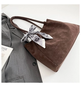 Detail of dark brown tote bag with printed silk scarf and textured matte finish leather