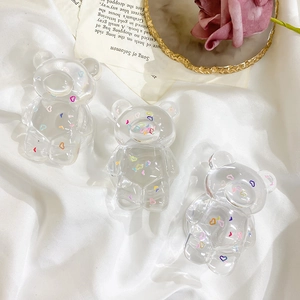 Close-up of three bear-shaped phone grips with colorful heart patterns on a stylish tray