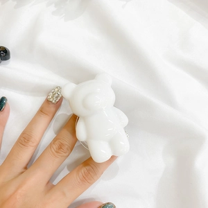 Close-up of a white bear-shaped phone grip on a silk background for hands-free support