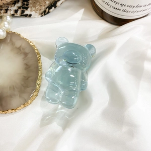 Detailed view of a light blue translucent bear phone grip on elegant fabric background