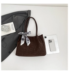 Close-up of brown suede tote bag with a decorative printed silk scarf on the handle