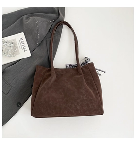 Detail of dark brown vintage tote bag with textured leather and paisley scarf on handle