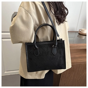 Dettaglio della borsa tote nera con goffratura a quadrifoglio e tracolla alla moda