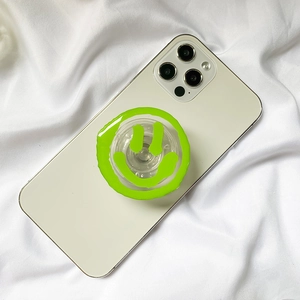 Detail view of a bright green smiley face phone socket stand on a white smartphone