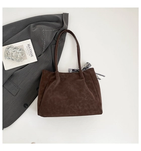 Flat lay of dark brown suede tote bag with geometric silk scarf and art book