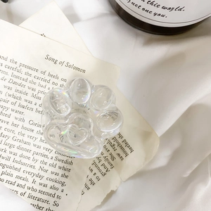 Detailed view of an iridescent cat paw phone stand on a vintage book page backdrop