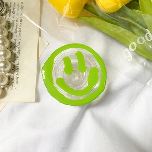Detail shot of a bright green melting smiley face phone grip on a white texture background