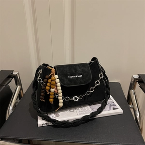 Black suede baguette bag with chain strap and beaded charm in a stylish setting