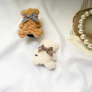 Detail of plush bear phone socket featuring a houndstooth bow on soft fabric background