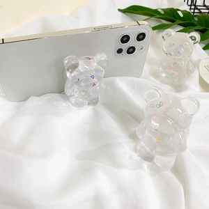 Close-up of three bear-shaped transparent resin phone grips with colorful heart sequins