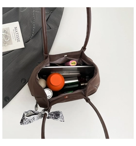 Macro view of a coffee brown tote bag's spacious interior showing laptop and daily essentials