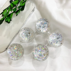 Detailed view of five spherical holographic glitter phone sockets on white fabric