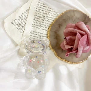 Transparent bear phone grip with colorful heart patterns on a vintage book background