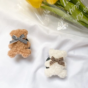 Detail of plush bear phone socket with soft fleece texture and plaid bow tie ornament