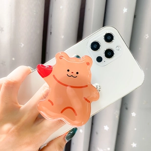 Close-up of a translucent orange bear acrylic griptok on a white mobile phone