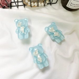 Dettaglio di tre simpatici orsetti 3D in resina blu su elegante tessuto di seta bianca
