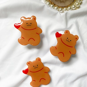 Detailed view of three cute yellow bear acrylic phone grips with red heart accents