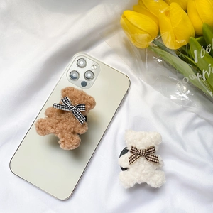 Detail showing brown and white teddy bear plush phone grips with plaid bow ties