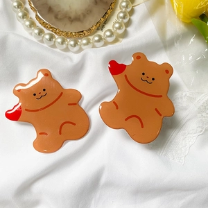 Close-up of cute brown bear resin hair accessories on a soft white fabric background