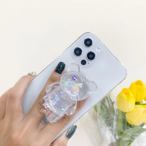 Detailed view of clear bear phone grip with colorful sequins on a white smartphone